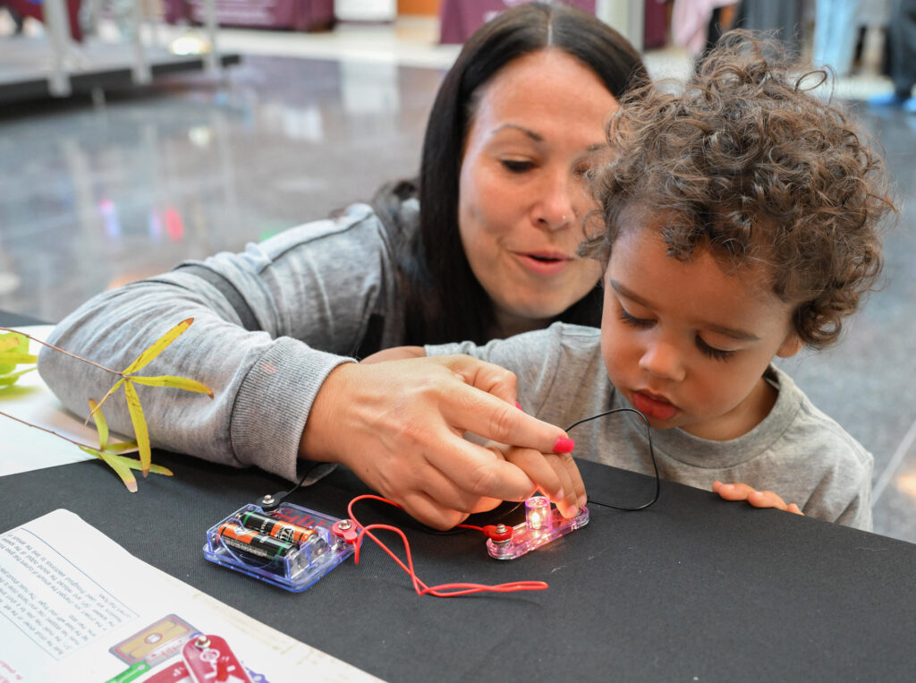 Erica Hickerson of Salisbury helps her son, Zakai, 2, complete an electric circuit to light a bulb during the UMES Extension 4-H STEM event Oct. 19, 2024 on the University of Maryland Eastern Shore campus. Photo by Todd Dudek/Ag Communications