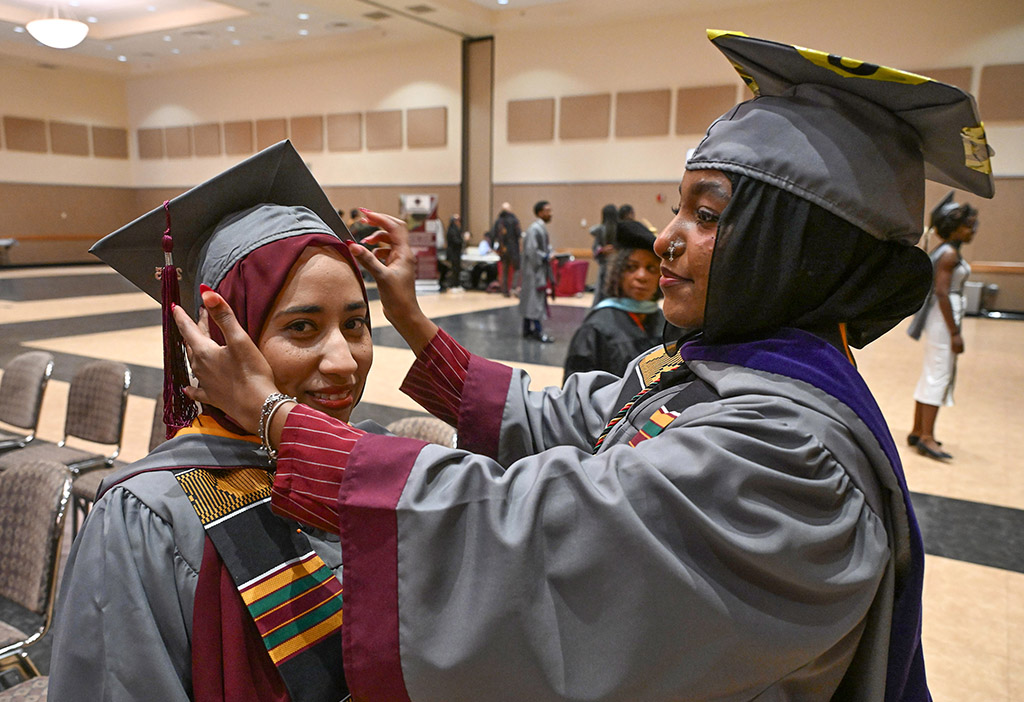 Manhal Amer, Biology major, gets help from Samreen Elamahdy to adjust her mortar board during the 139th Spring Commencement.