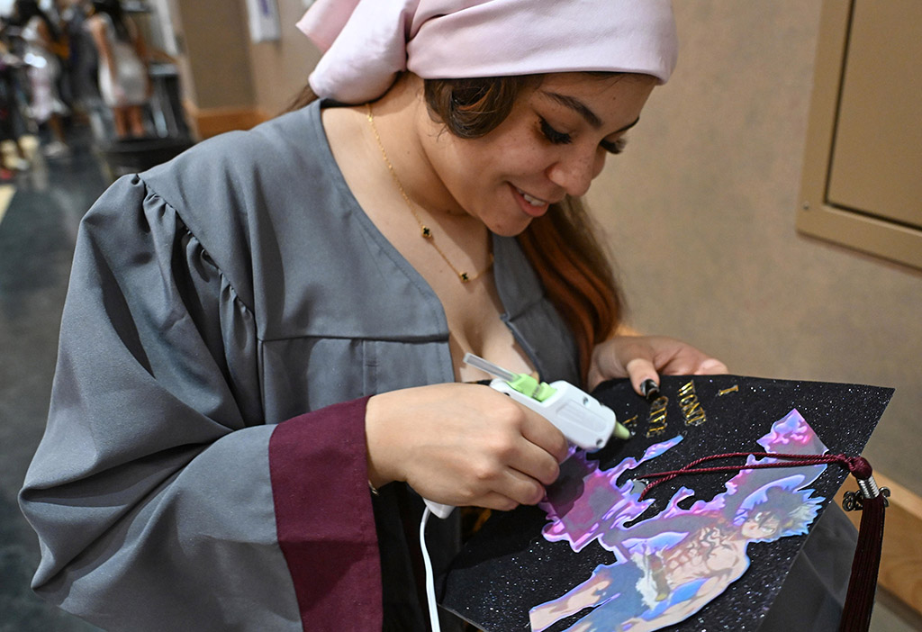 General Agricultural Studies graduate Kaila Tyree-Castro glues letters on her mortar board before the 139th Spring Commencement.