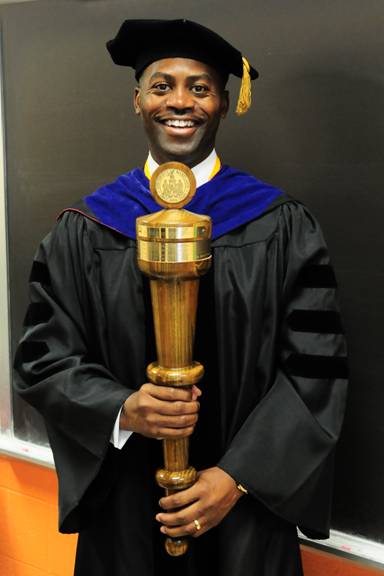 A faculty member carries the mace. 